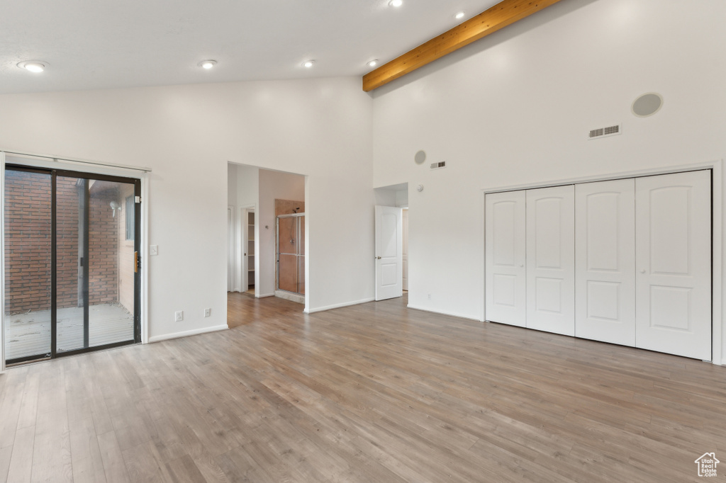 Unfurnished bedroom with high vaulted ceiling, access to outside, light wood-style floors, beamed ceiling, and recessed lighting