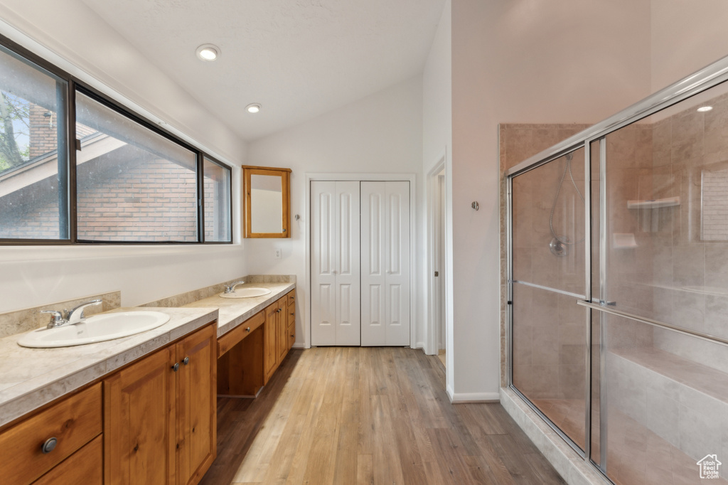 Full bath with two vanities, lofted ceiling, wood finished floors, a shower stall, and recessed lighting