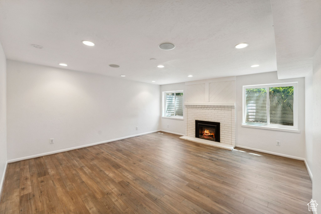 Unfurnished living room featuring healthy amount of natural light, baseboards, wood finished floors, and recessed lighting