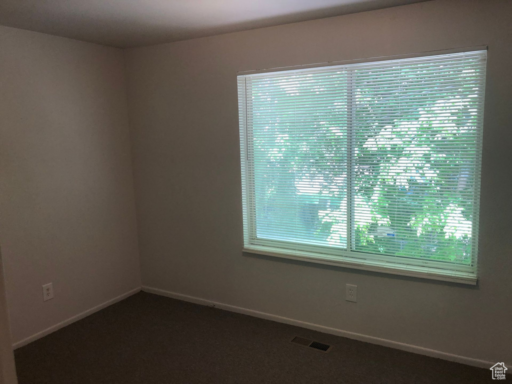 Empty room featuring dark colored carpet and baseboards