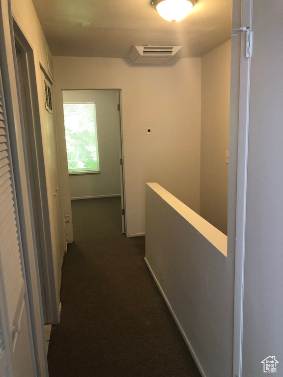 Corridor featuring an upstairs landing and dark carpet