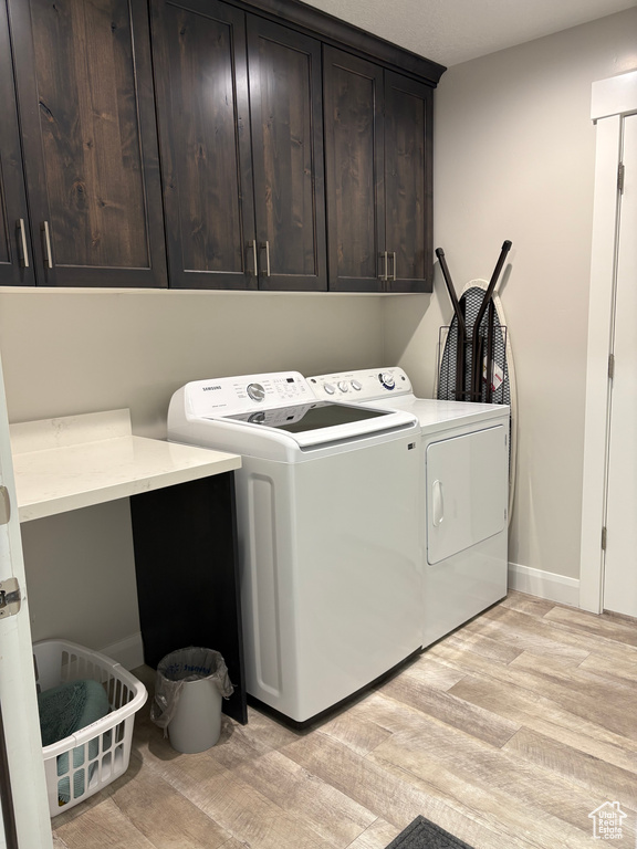 Laundry area featuring cabinet space, washing machine and dryer, and light wood-type flooring