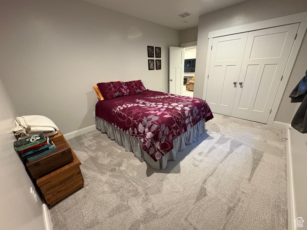 Bedroom with light carpet, baseboards, and a closet