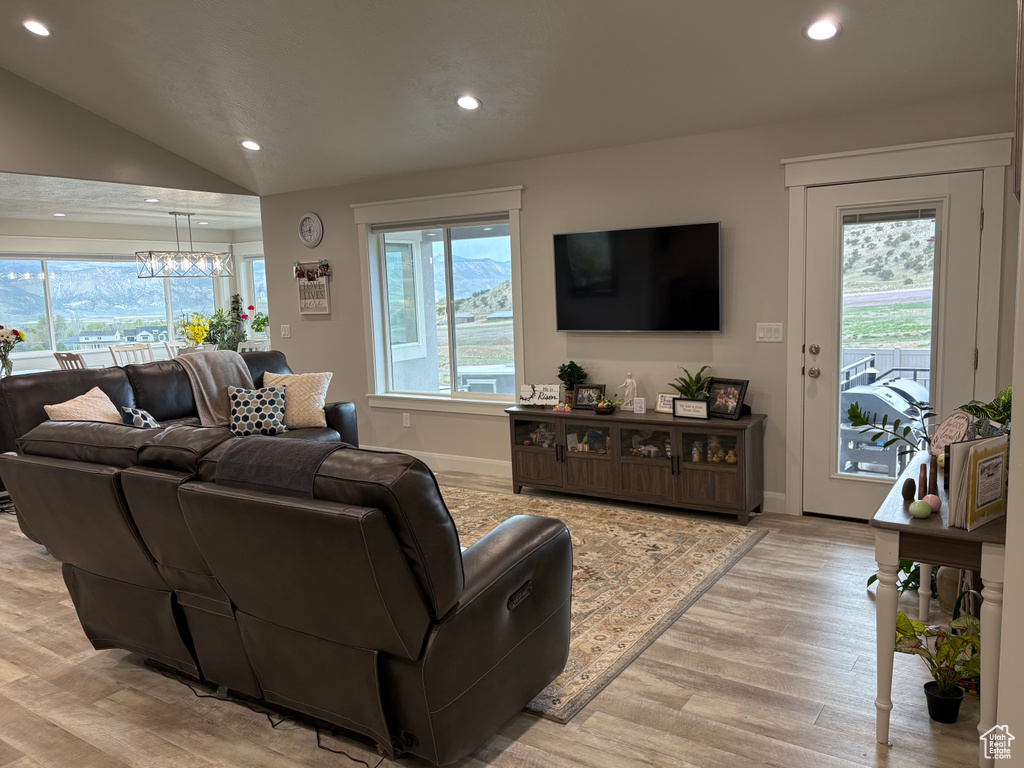Living room featuring recessed lighting, light wood-type flooring, plenty of natural light, a chandelier, and lofted ceiling