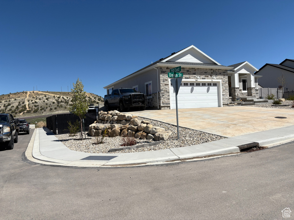 View of front facade featuring driveway, stone siding, and an attached garage