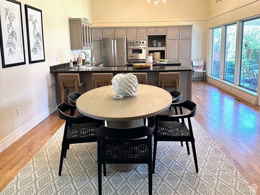 Dining area featuring high vaulted ceiling, a chandelier, light wood-type flooring, and baseboards