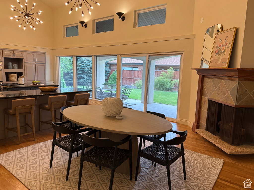 Dining room featuring high vaulted ceiling, a tile fireplace, a chandelier, and light wood-style floors