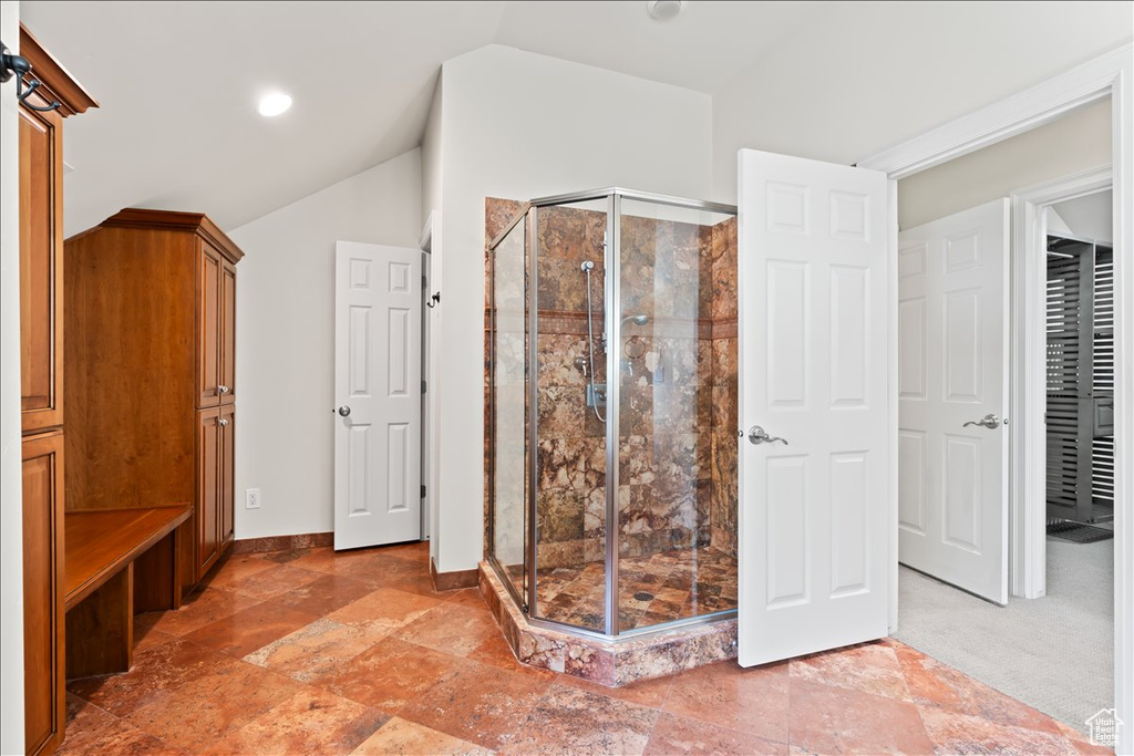 Unfurnished bedroom featuring lofted ceiling, baseboards, and stone finish floors