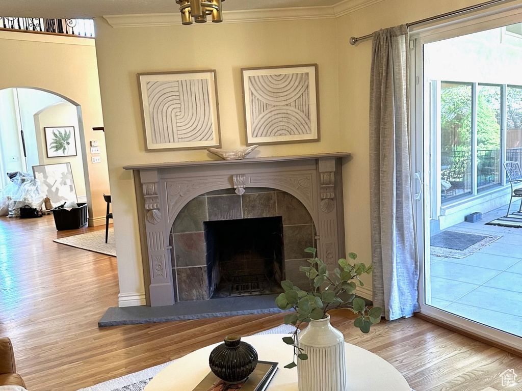 Living area with wood finished floors, a tiled fireplace, and crown molding