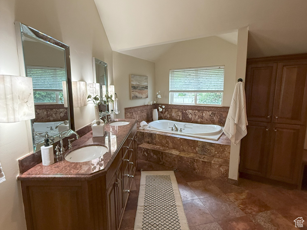 Bathroom featuring a garden tub, double vanity, and high vaulted ceiling