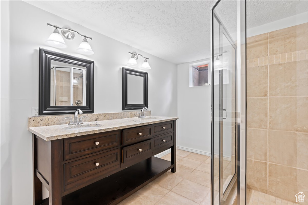 Bathroom featuring double vanity, a shower stall, a textured ceiling, and tile patterned floors