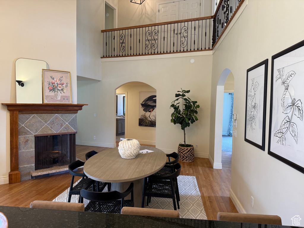 Dining room with arched walkways, a high ceiling, wood finished floors, a fireplace, and baseboards