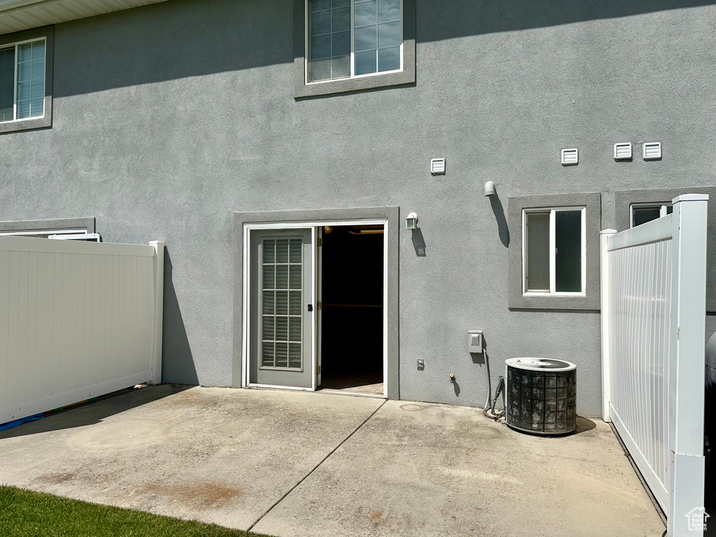 Rear view of house with a patio, central AC, and stucco siding