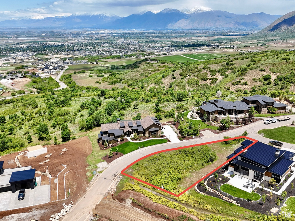 Aerial perspective of suburban area featuring property boundaries highlighted and a mountain backdrop