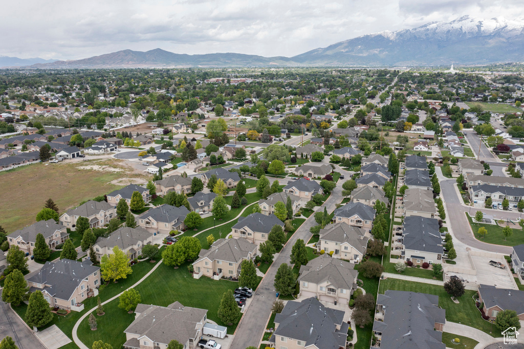 Aerial view of property and surrounding area featuring a mountainous background and nearby suburban area