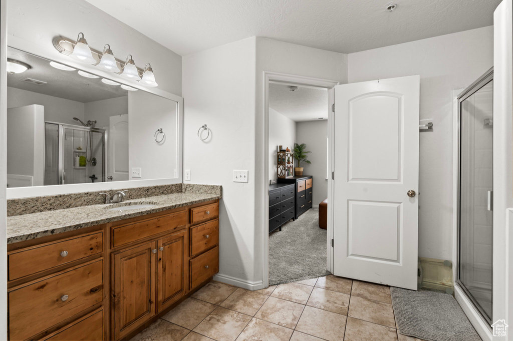 Full bathroom featuring a shower stall, vanity, and tile patterned floors