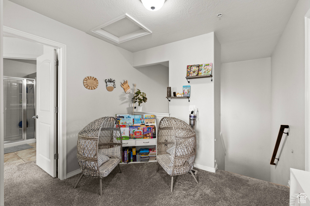 Living area with attic access, an upstairs landing, carpet flooring, and baseboards