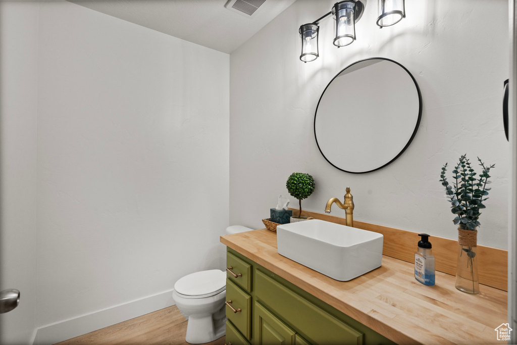 Bathroom with wood finished floors, vanity, toilet, and baseboards