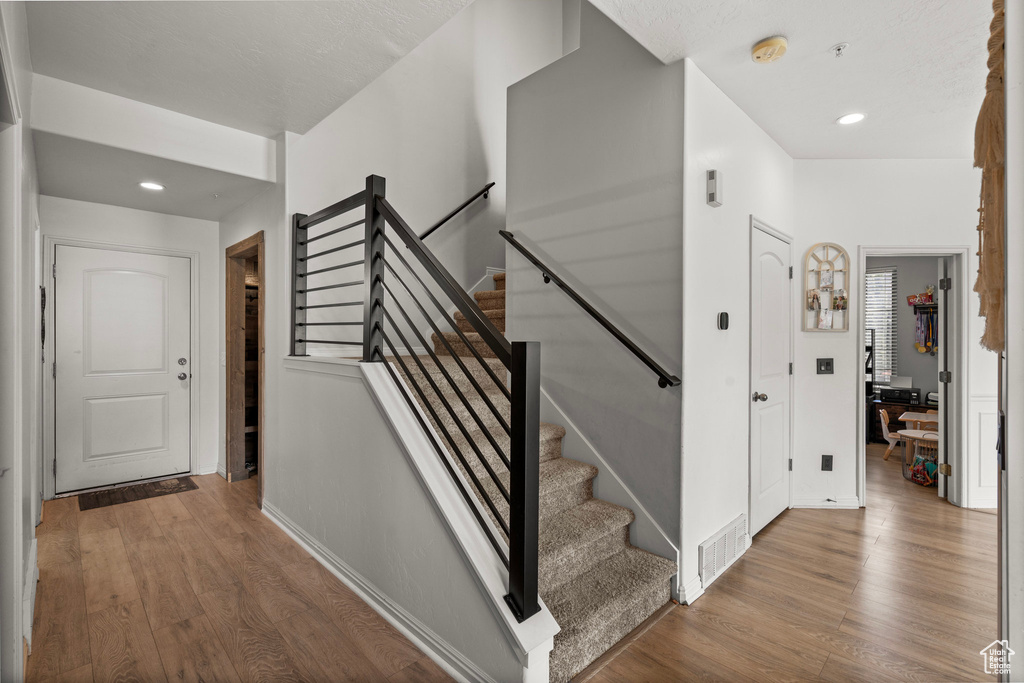 Stairs with wood finished floors, baseboards, and recessed lighting
