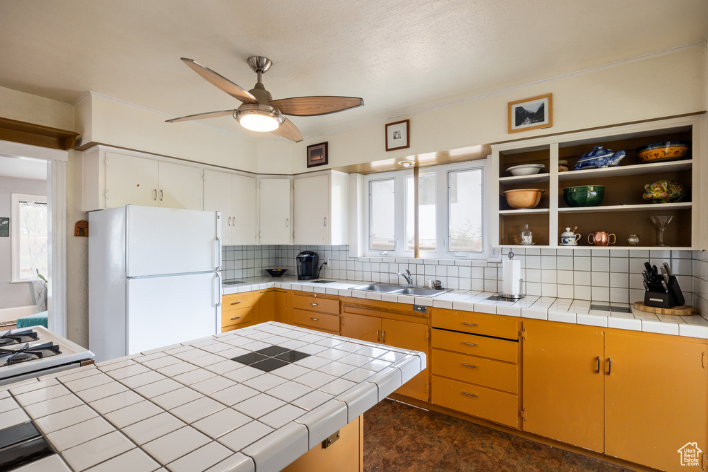 Kitchen featuring freestanding refrigerator, a sink, tasteful backsplash, and ceiling fan