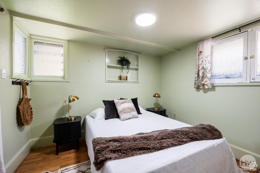 Bedroom with multiple windows and wood finished floors