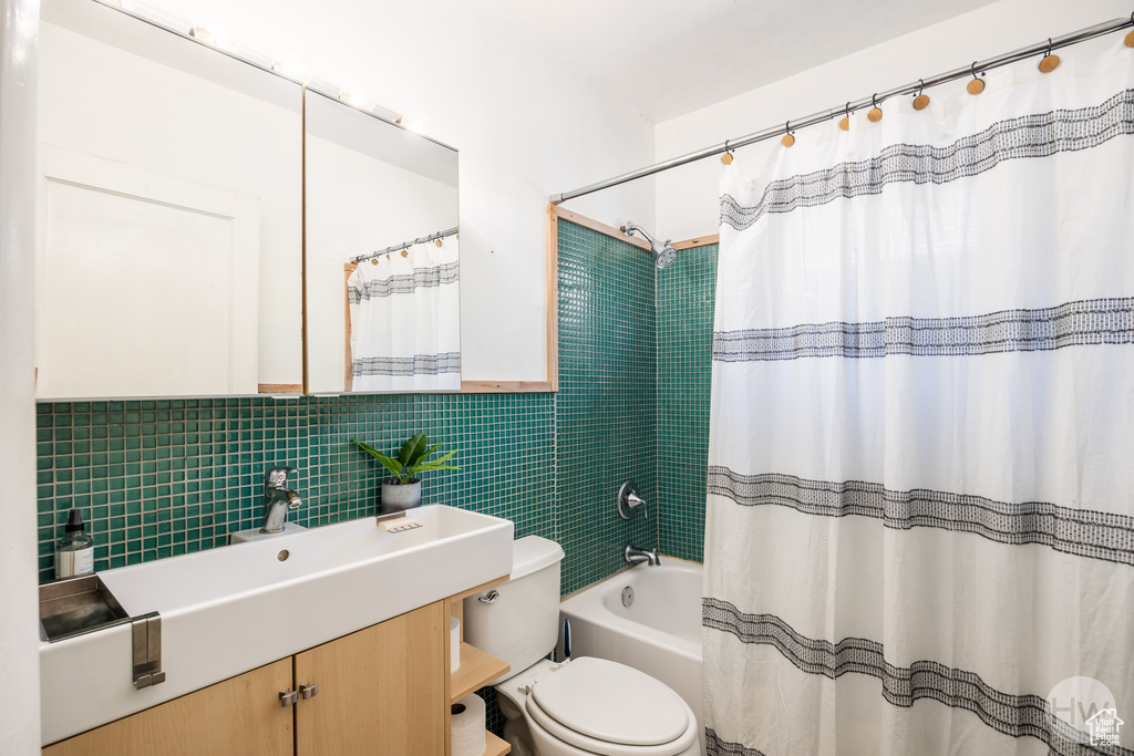 Bathroom featuring vanity, tile walls, shower / tub combo, and decorative backsplash