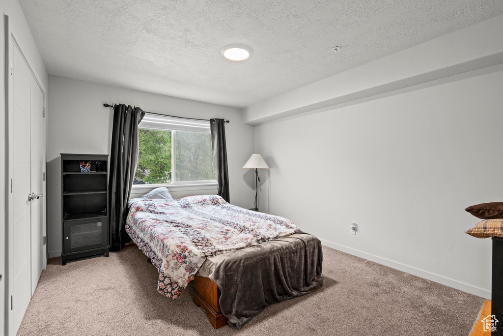 Carpeted bedroom with a textured ceiling and baseboards