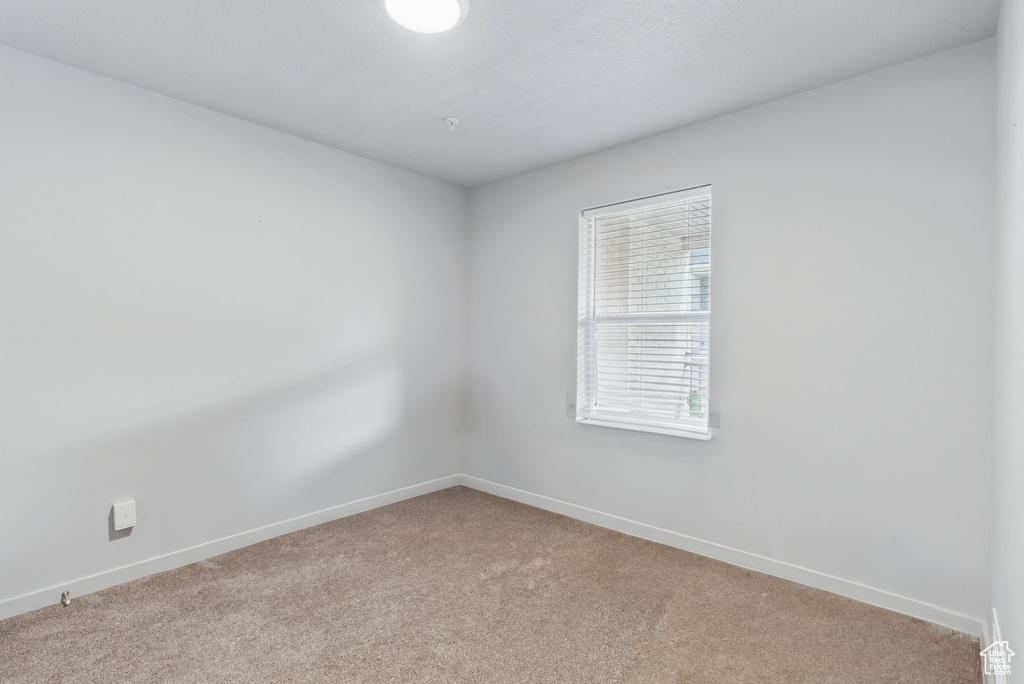 Empty room featuring light carpet and baseboards