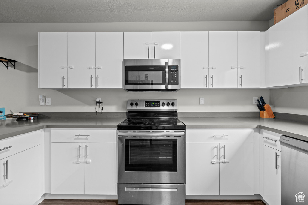 Kitchen featuring appliances with stainless steel finishes, white cabinets, and wood finished floors