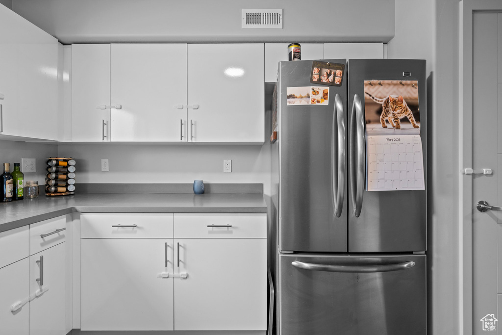 Kitchen with freestanding refrigerator and white cabinetry