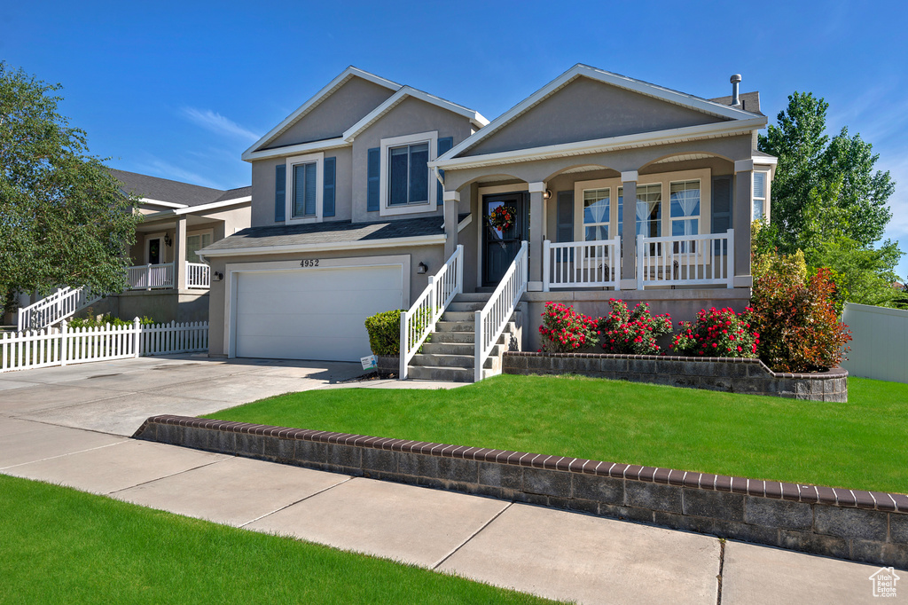 Tri-level home featuring covered porch, concrete driveway, a garage, and stucco siding