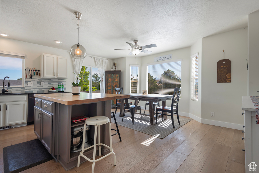 Kitchen featuring a sink, a breakfast bar, tasteful backsplash, light wood finished floors, and butcher block countertops