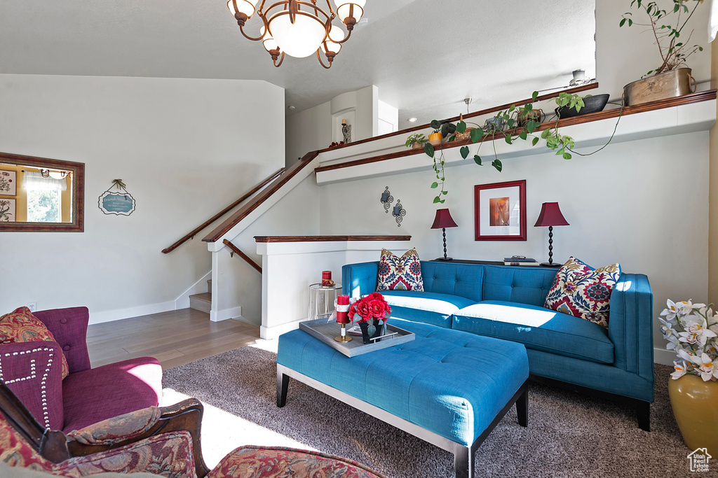 Living area featuring wood finished floors, a chandelier, baseboards, and stairway