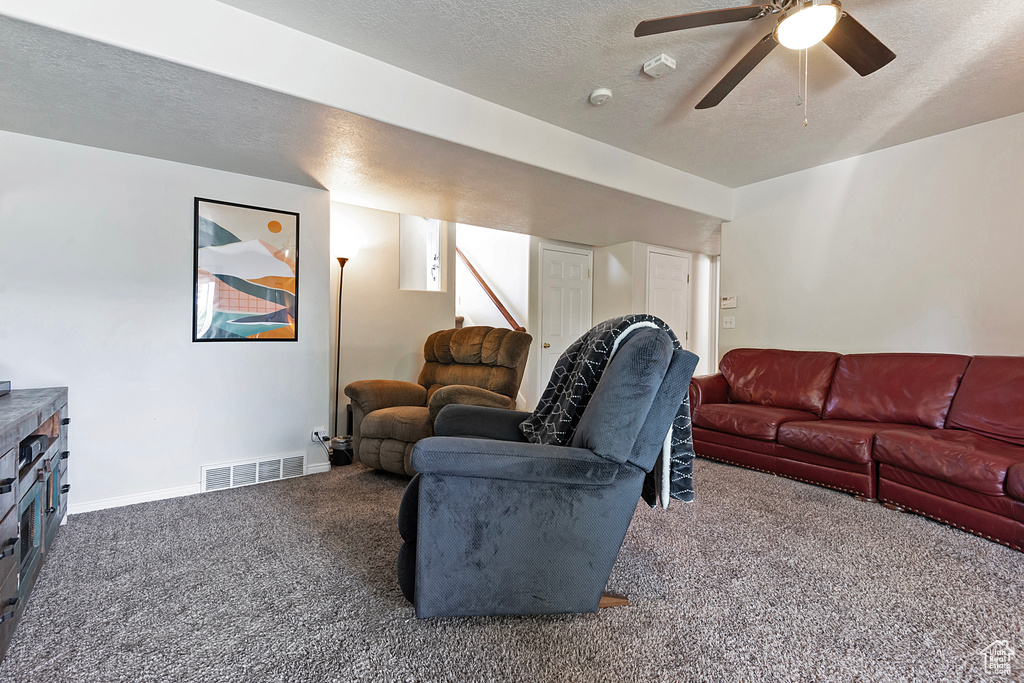 Living room with carpet, a textured ceiling, ceiling fan, and baseboards