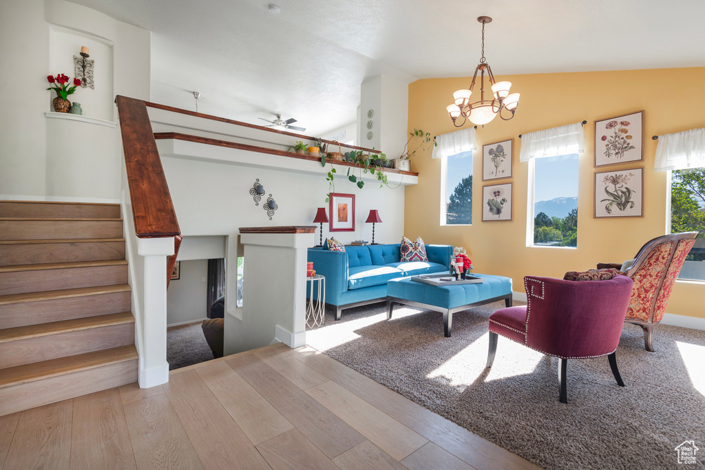 Living area with lofted ceiling, wood finished floors, stairway, ceiling fan, and a chandelier