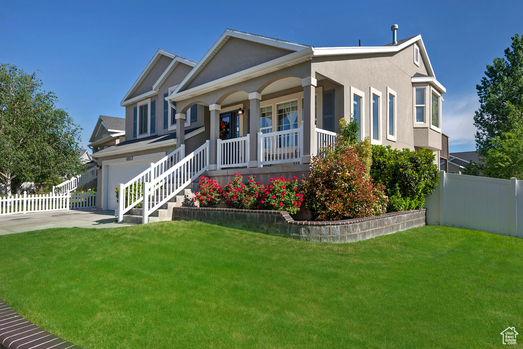 View of front facade with covered porch, a garage, stucco siding, and driveway