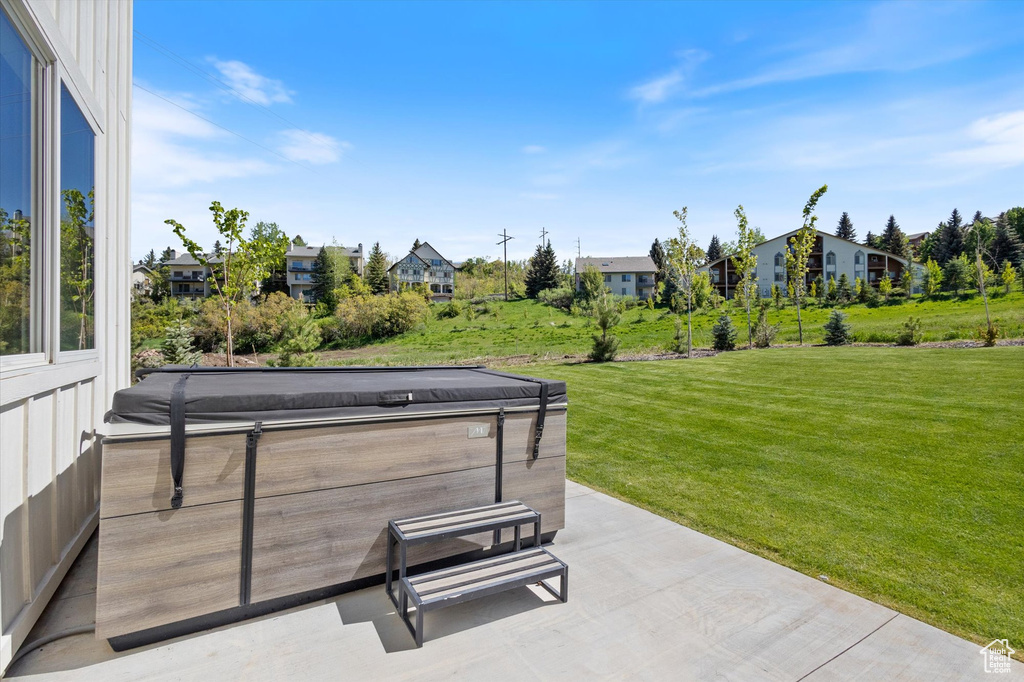 View of patio / terrace featuring a hot tub and a residential view