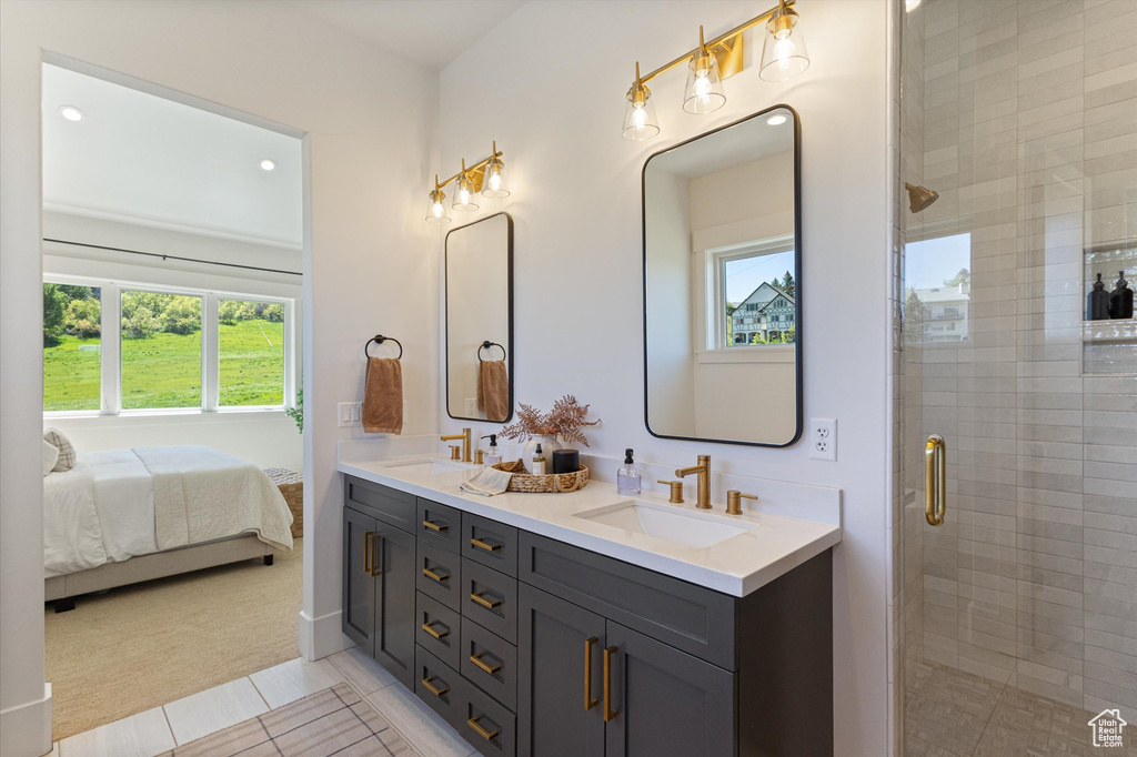 Ensuite bathroom with double vanity, plenty of natural light, a shower stall, and tile patterned flooring