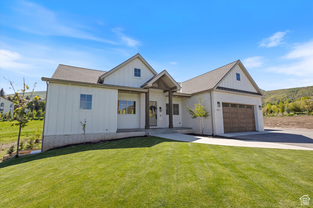Modern farmhouse style home featuring board and batten siding, driveway, a garage, and a front lawn