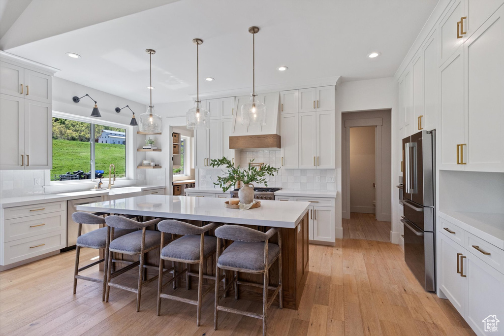 Kitchen featuring appliances with stainless steel finishes, a breakfast bar area, decorative backsplash, white cabinetry, and a center island