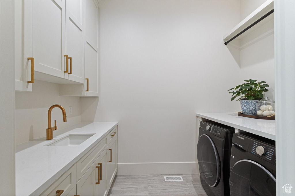 Washroom with washing machine and dryer, cabinet space, and baseboards