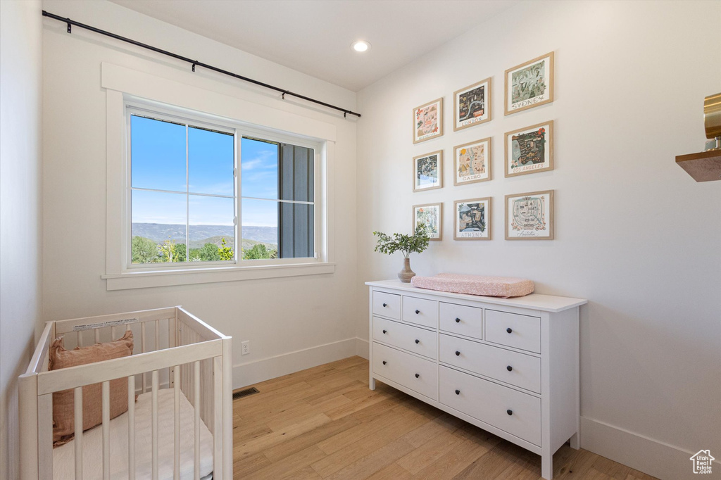 Bedroom featuring baseboards, light wood-type flooring, a nursery area, and recessed lighting