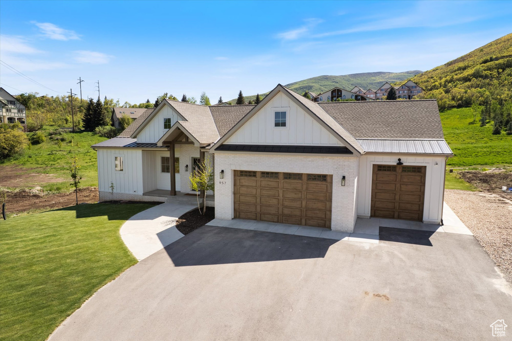 Modern inspired farmhouse featuring board and batten siding, driveway, a front yard, and a mountain view