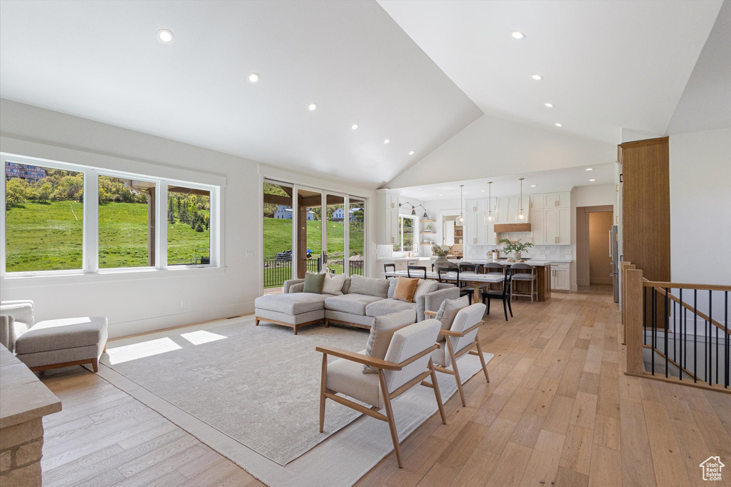 Living room with high vaulted ceiling, light wood-style floors, and recessed lighting