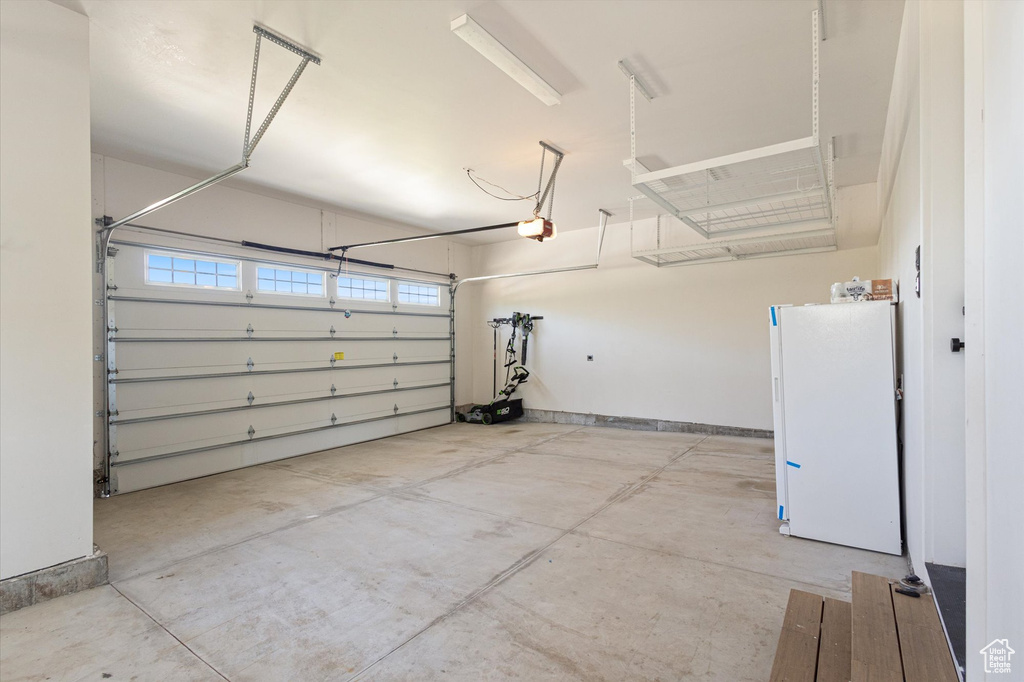 Garage featuring freestanding refrigerator and a garage door opener