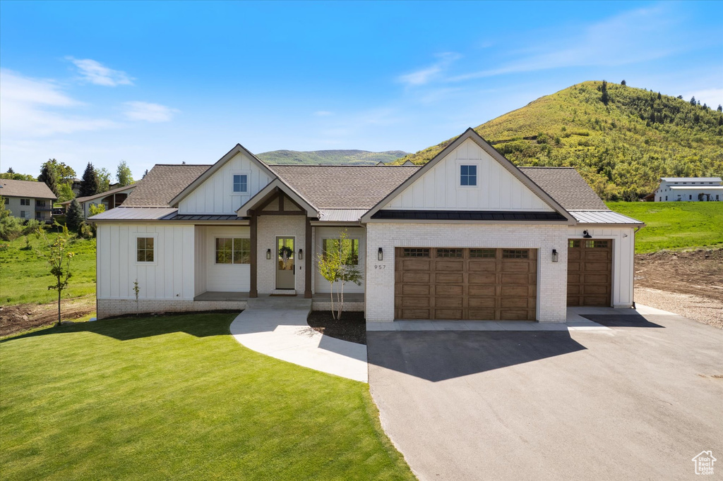Modern farmhouse style home with board and batten siding, driveway, a front yard, and roof with shingles