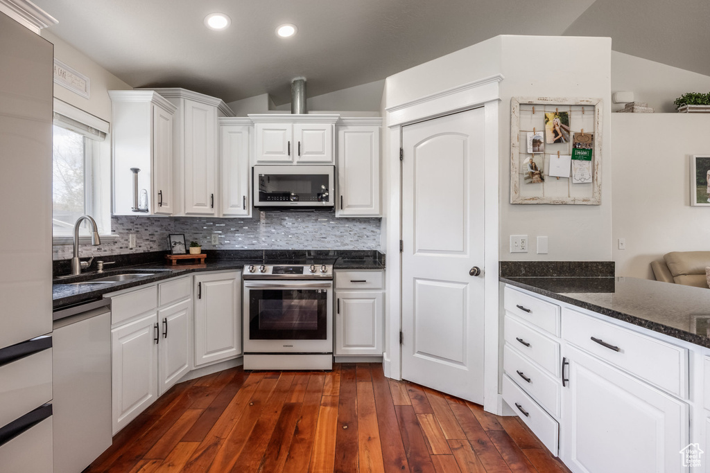 Kitchen featuring appliances with stainless steel finishes, white cabinets, a sink, dark wood-type flooring, and recessed lighting