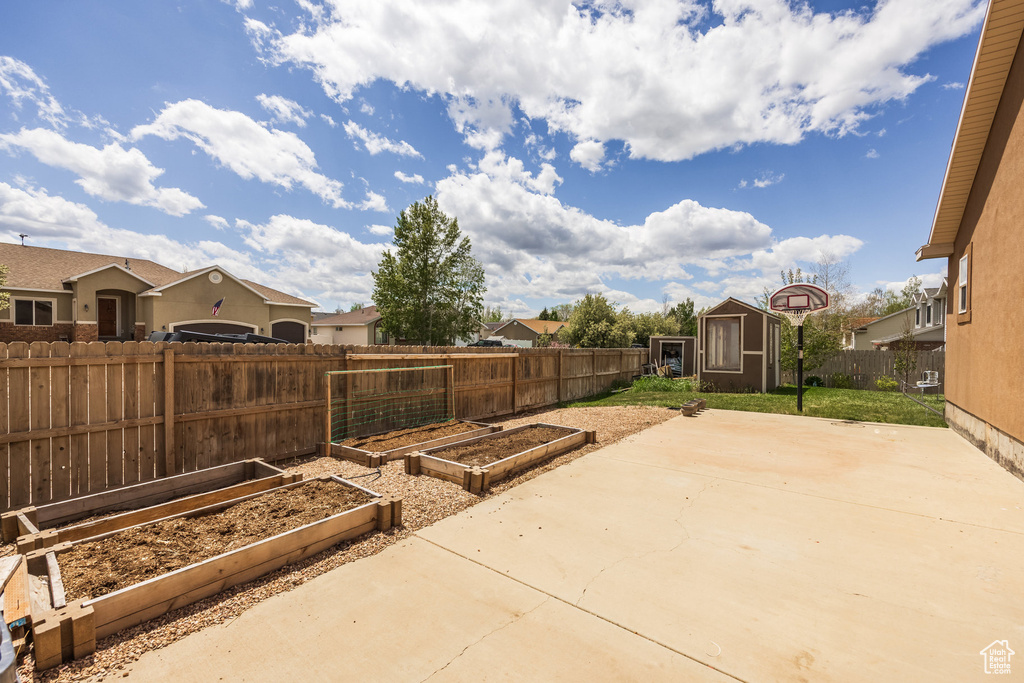 Fenced backyard with a vegetable garden and a patio area