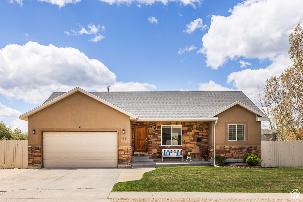 View of front facade with stone siding, covered porch, a garage, and stucco siding