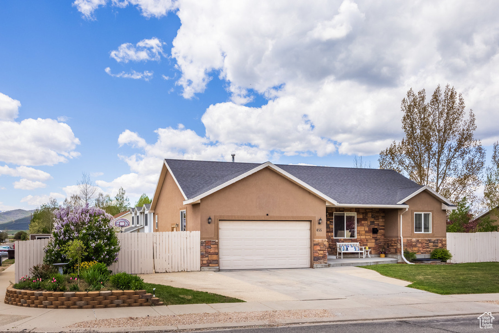 View of front of property with stone siding, a garage, concrete driveway, and stucco siding
